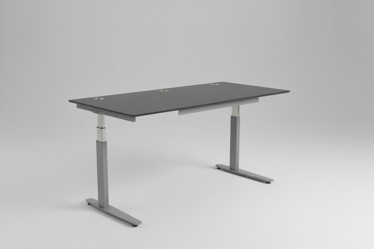 Brugt Duba hæve-sænkebord 180x80 i antracitgrå set fra skrå vinkel, med affasede kanter, kabelbakke og kabelgennemføring.